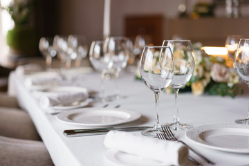 Table setting in the restaurant, glasses in the foreground. Luxury wedding reception. Flower arrangement on table in restaurant. Stylish decor and adorning.