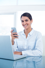 Obraz na płótnie Canvas Smiling businesswoman using her smartphone