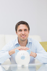 Fototapeta na wymiar Handsome casual man with piggy bank in living room