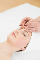 Fototapeta na wymiar Hands massaging a beautiful womans forehead