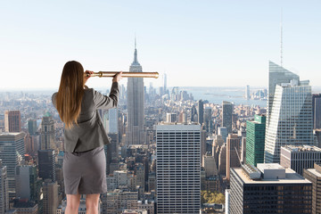 Businesswoman looking through a telescope against city skyline