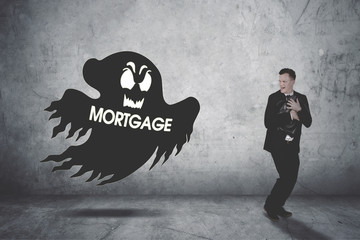 Businessman running scare being chased by a mortgage ghost