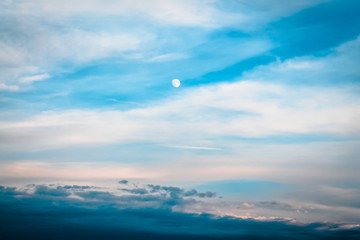 The start of sunset while the moon is high in the sky