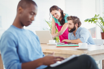 Fototapeta premium Woman pointing at laptop while discussing with man at desk 