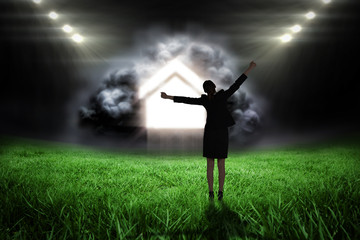 Fototapeta na wymiar Excited businesswoman cheering against football pitch with bright lights