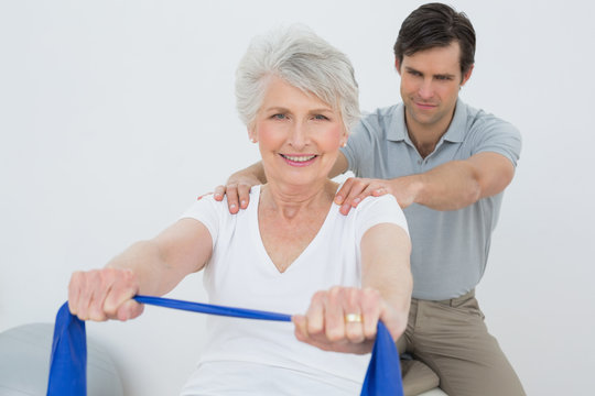 Male therapist assisting senior woman with exercises
