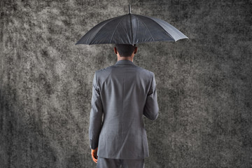 Businessman standing under umbrella against grey background