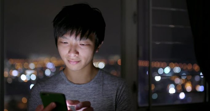 Man use of mobile phone at home in the evening