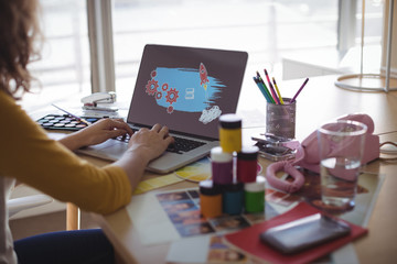 Cropped image of businesswoman typing on laptop at office