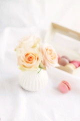 Blur effect, soft focus macaroons in pastel colors with bouquet of cream  roses flowers on a white   background.Beautiful Holiday background.copy space.top view