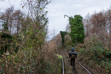 Fototapeta na wymiar Guy going by rail with a backpack between high thickets