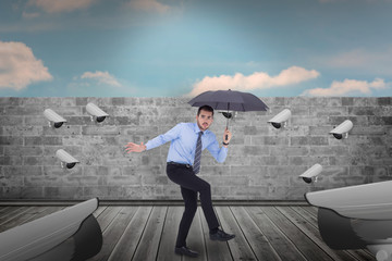 Obraz premium Anxious businessman under umbrella balancing against blue sky over brick wall