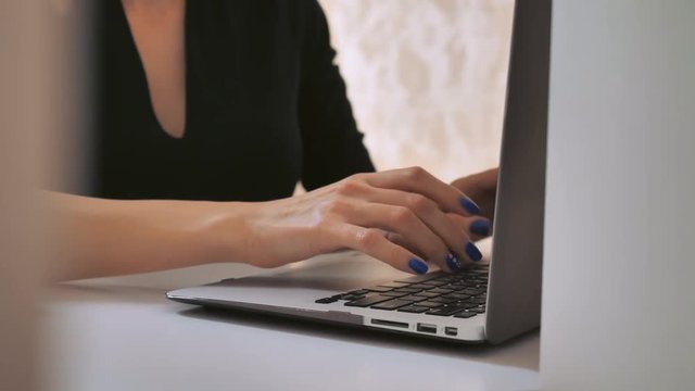business details unrecognizable woman typing on laptop. female fingers with blue nail polish entering data on computer