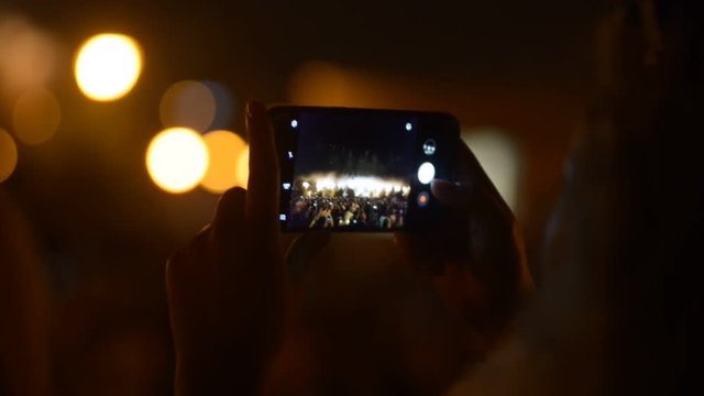 Close up of woman taking photos of fireworks on her smartphone. Concept: people, summer, festival, crowd, firework, night