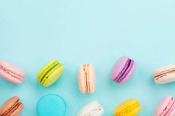 Macaron or macaroon on turquoise pastel background from above. Colorful almond cookies on dessert...