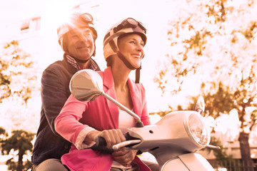 Fototapeta na wymiar Happy senior couple riding a moped on a sunny day