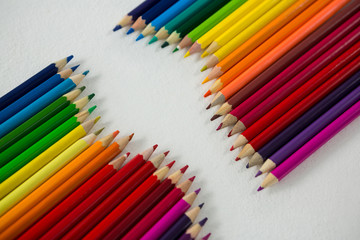 Colored pencils arranged in a row on white background