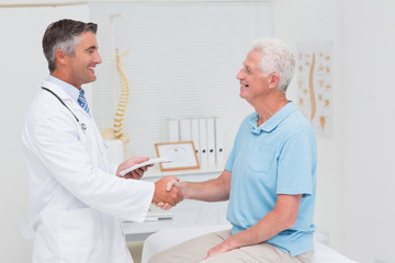 Male doctor and senior patient shaking hands