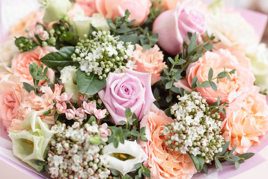 pastel orange and lilac bouquet of beautiful flowers on wooden table. Floristry concept. Spring colors. the work of the florist at a flower shop. Vertical photo