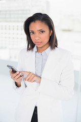 Stern young dark haired businesswoman using a mobile phone