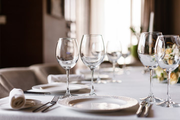 Table setting in the restaurant, glasses in the foreground. Luxury wedding reception. Flower...