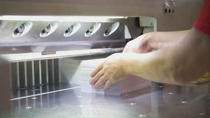 Female worker folds a stack of paper in the typography