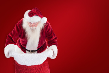 Santa looks in his bag against red background