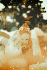 Festive little girl in hat and scarf against candle burning against festive background