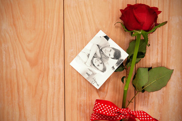 Smiling beatiful couple sitting on a sofa against red heart envelope and a red rose