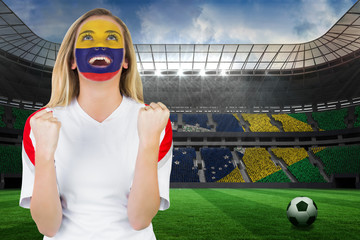 Excited colombia fan in face paint cheering against large football stadium with brasilian fans