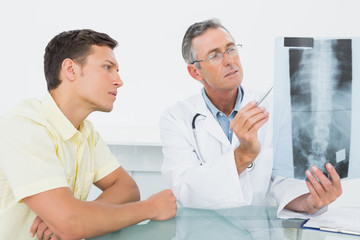 Doctor explaining spine xray to patient in office