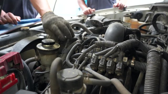 4k movie of mechanic repairing an old car. Under the hood of the car checks the work of carb and engine