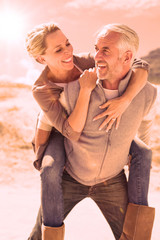 Laughing couple smiling at each other on the beach on a bright but cool day