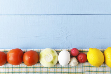 Raw egg, tomatoes, onion, garlic and lemon on wooden background. Uncooked ingredients for healthy breakfast. Top view