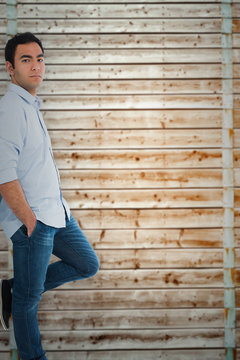 Unsmiling casual man standing against wooden background in pale wood