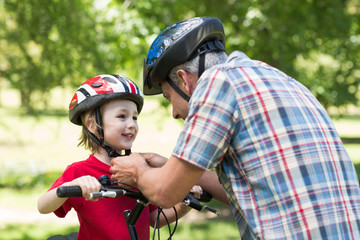 Fototapeta na wymiar Father attaching his sons cycling helmet 