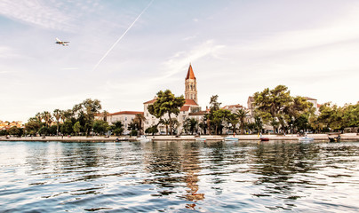 Trogir with Cathedral of St. Lawrence, water at sea and an airplane flies