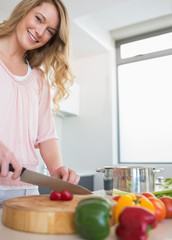 Obraz na płótnie Canvas Happy woman chopping vegetables on board