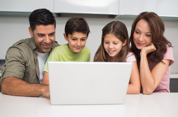Smiling couple with kids using laptop