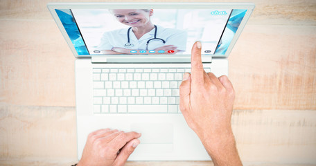 Happy doctor looking at camera with arms crossed  against hand pointing on blank laptop screen