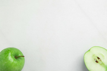 Whole and Half Ripe Green Organic Apple with Seeds on White Marble Background. Visible Texture. Creative Minimalist Image for Culinary Vegan Website. Banner Streamer Poster Template. Health Wellness