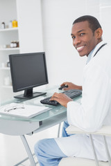 Smiling male doctor using computer at medical office