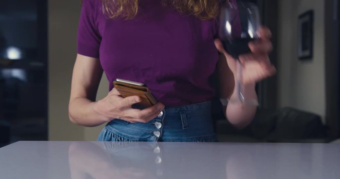 Young woman using smartphone and drinking wine