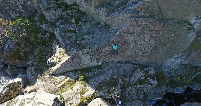 Climber is a man on a training climb on a rock among a granite canyon. Aerial view