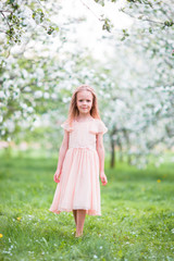 Fototapeta na wymiar Little beautiful girl enjoying smell in a flowering spring garden