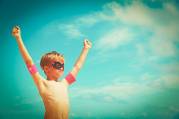 little boy play superhero at sky on beach