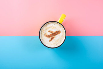 Coffee cappuccino with a picture of the airplane on the foam, top view. Pastel bright background. Concept of air travel.