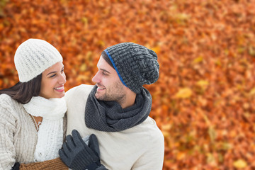 Young winter couple against autumn leaves on the ground
