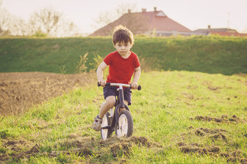 Boy rides a balance bike in the countryside