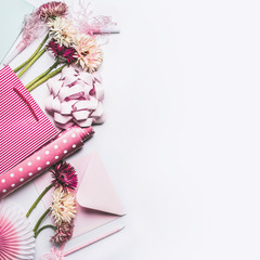 Greeting accessories setting with flowers,  bow, ribbon, pink gift wrapping paper and shopping bag on white desktop background, Top view , copy space, flat lay